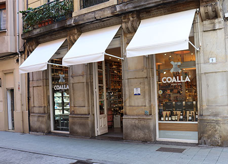 Vista exterior del comercio, dónde se puede ver la puerta de entrada y los dos escaparates a ambos lados de la misma