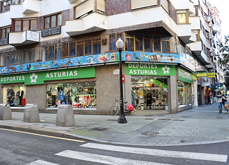 Vista exterior de la tienda, dónde podemos ver la entrada haciendo esquina y los tres escaparates, dos a una calle y el tercero a la otra