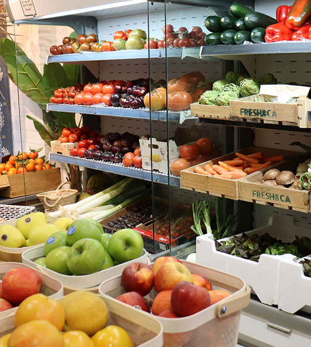 Vista del interior del comercio, dónde podemos ver dos expositores con cajas de fruta y verduras. En primer plano vemos unas cestas con fruta.