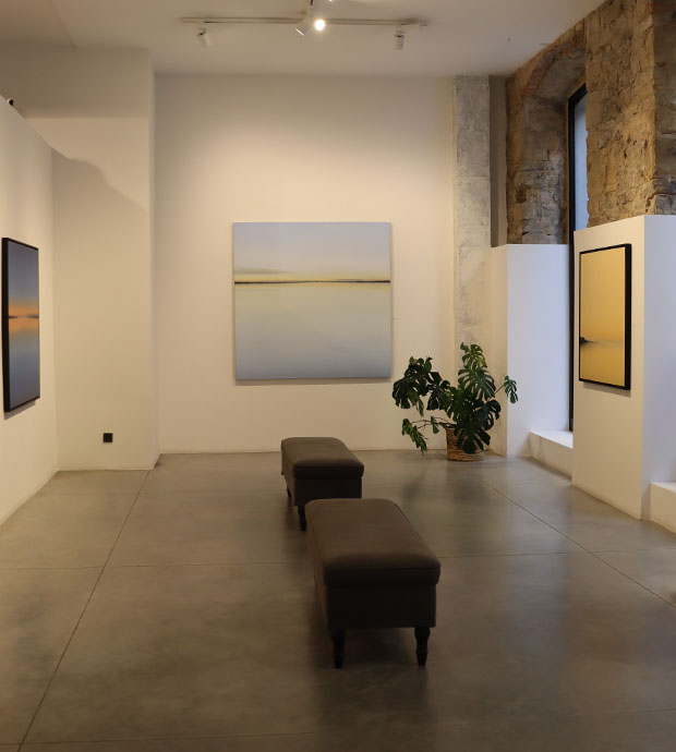 Vista del interior de la galería, dónde podemos ver tres cuadros dispuestos en tres paredes de una habitación, con dos bancos situados en el medio de la misma