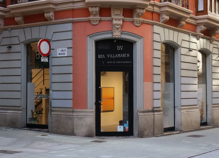 Vista del exterior de la galería, dónde podemos ver la entrada a la misma situada en una esquina y los ventanales que permiten ver el interior de la misma