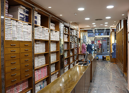 Vista del interior del comercio, dónde se puede ver el mostrador de madera y las estanterías con material. Al fondo se ve la entrada del mismo.