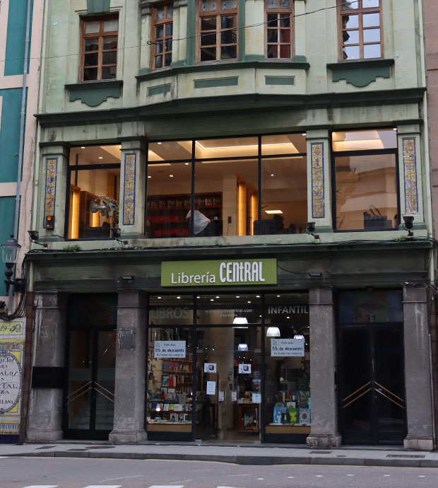 Vista de la entrada de la tienda, dónde se pueden ver los dos escaparates y la puerta situada entre ellos. También se ve la planta superior de la librería.