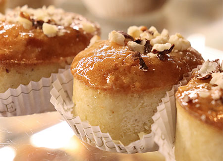 Primer plano de pasteles de bizcocho cubiertos con almíbar y nueces sobre un papel de magdalena