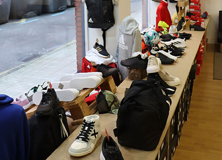 Vista interior de un escaparate, dónde podemos ver ropa, deportivas y mochilas