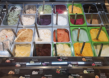 La vitrina pequeña de helados, con 22 sabores más especializados, de fondo las estanterías donde están los recipientes, cucuruchos y otros elementos