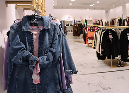 Vista del interior de la tienda, dónde podemos ver varios percheros, tanto de pared como de suelo, con ropa de diversos estilos en ellos