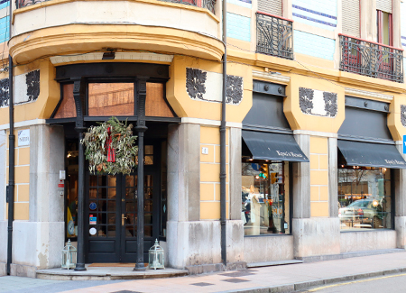 Vista del exterior del comercio, dónde se puede ver la entrada, situada en una esquina, y dos de los escaparates que dan a la misma calle