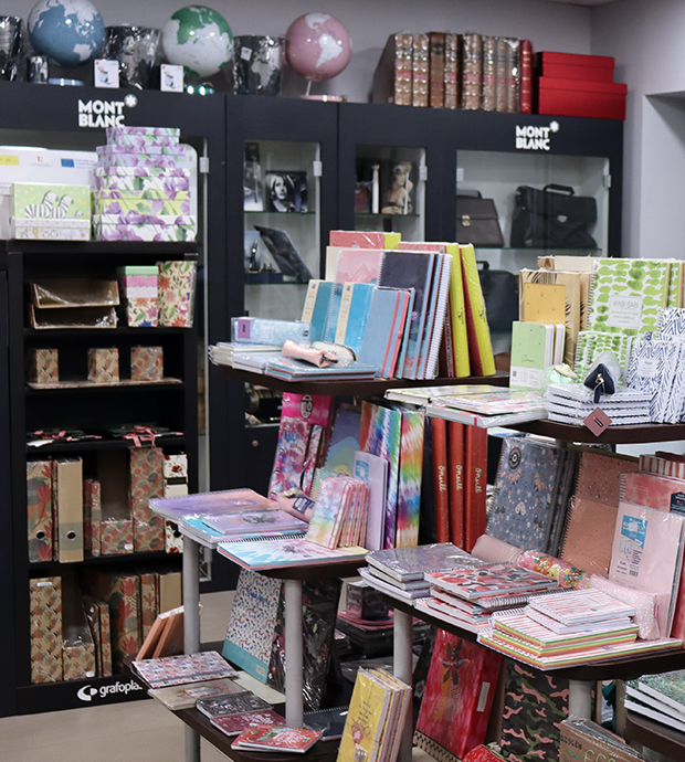 Vista del interior de la librería, dónde podemos ver en primer plano dos expositores con diverso material de papelería y al fondo una estantería de Mont Blanc con más material así como marcos para fotos, maletines y otros productos