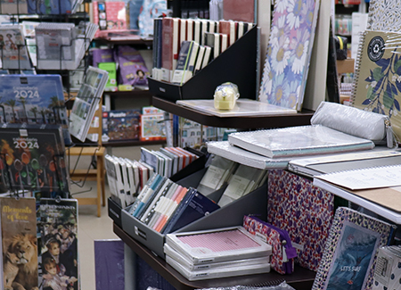 Vista del interior de la librería dónde podemos ver expositores con productos de papelería, junto a un expositor vertical con calendarios de 2024